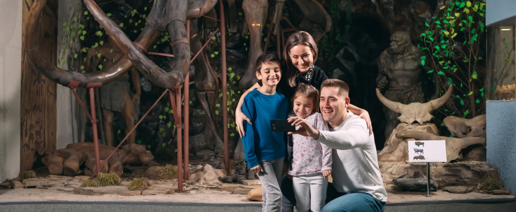 A family smiling and observing artifacts in a museum